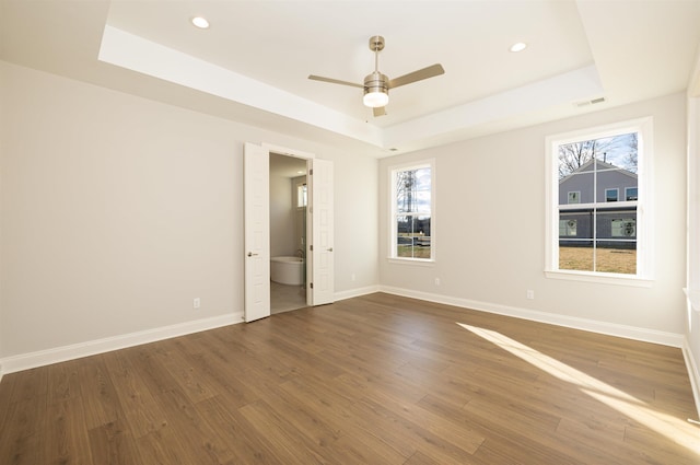 spare room featuring a raised ceiling, ceiling fan, and dark hardwood / wood-style flooring