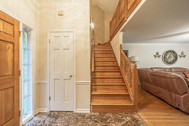 stairway featuring crown molding, hardwood / wood-style floors, and a textured ceiling