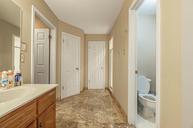 bathroom with vanity, toilet, an enclosed shower, and a textured ceiling