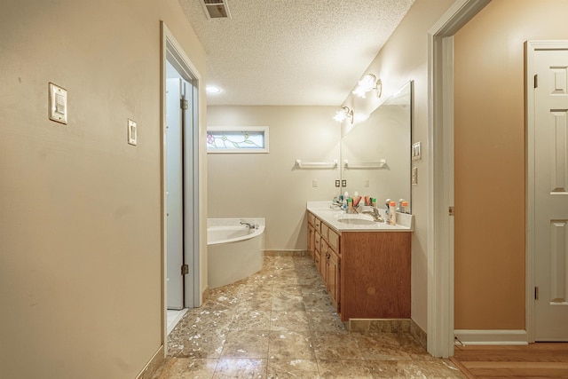 bathroom featuring a tub to relax in, vanity, and a textured ceiling