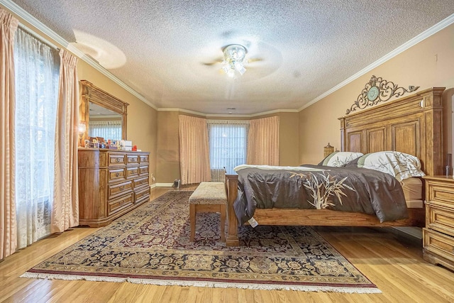 bedroom with a textured ceiling, ornamental molding, ceiling fan, and light wood-type flooring