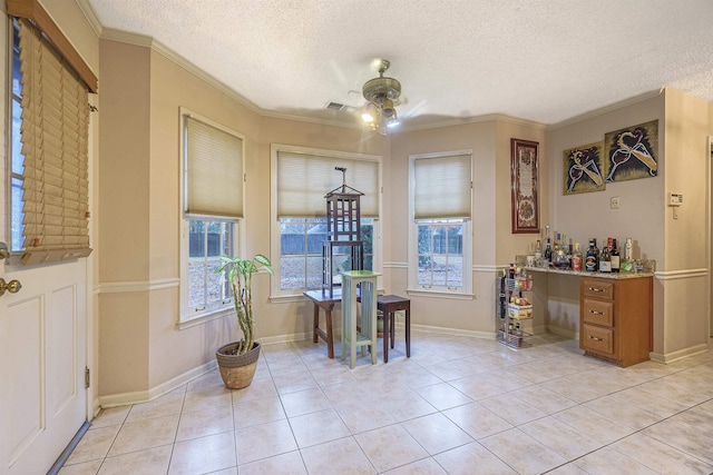 tiled dining space featuring ceiling fan, ornamental molding, bar area, and a textured ceiling