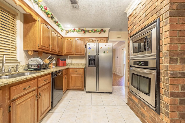 kitchen featuring light tile patterned flooring, appliances with stainless steel finishes, sink, and a textured ceiling