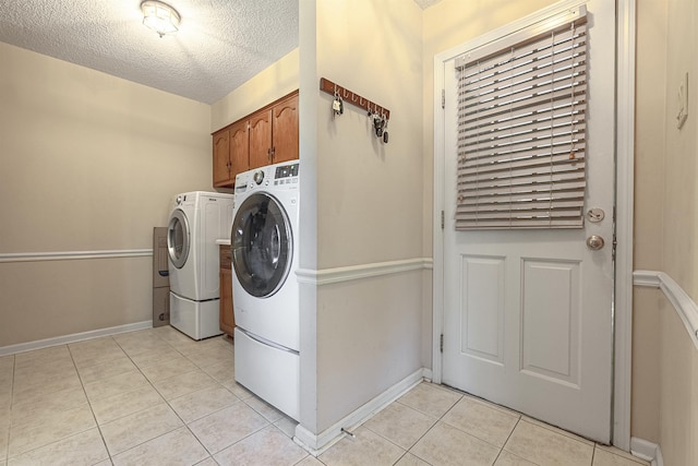 washroom featuring cabinets, light tile patterned floors, washer and dryer, and a textured ceiling