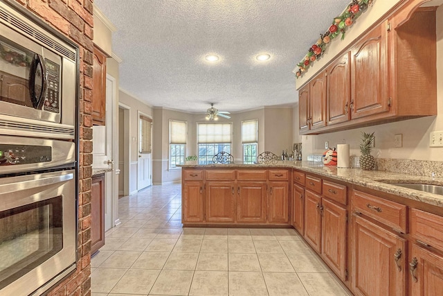 kitchen featuring light tile patterned flooring, kitchen peninsula, a textured ceiling, and appliances with stainless steel finishes