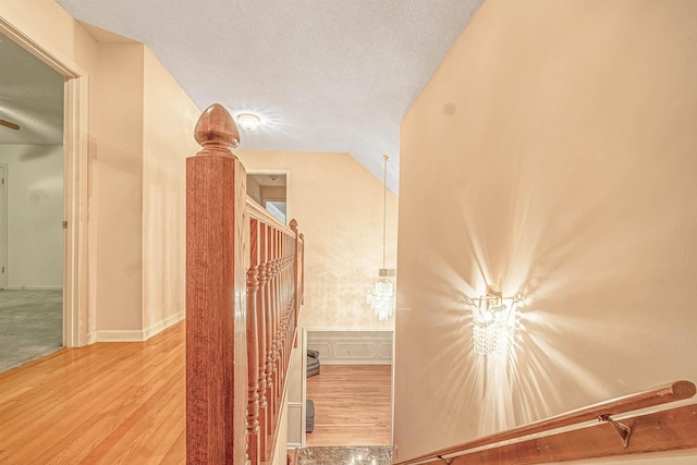 stairs featuring lofted ceiling, hardwood / wood-style floors, and a textured ceiling