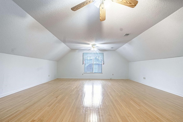 additional living space featuring ceiling fan, lofted ceiling, light hardwood / wood-style flooring, and a textured ceiling