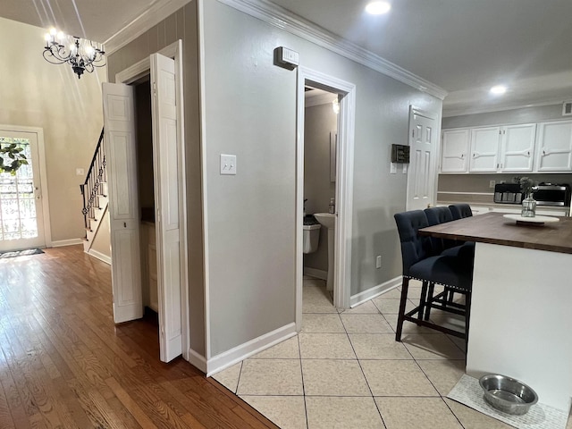 interior space featuring a kitchen breakfast bar, white cabinetry, light hardwood / wood-style flooring, and ornamental molding