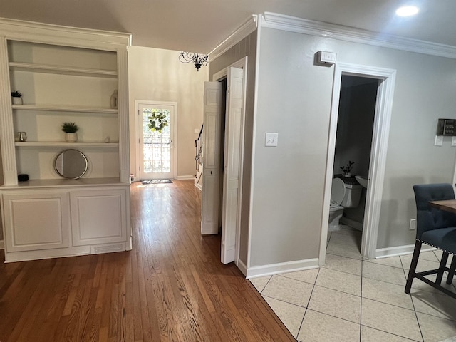 corridor with crown molding, light hardwood / wood-style flooring, and a chandelier