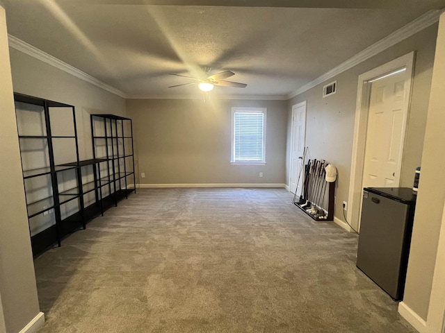 empty room with carpet flooring, ceiling fan, crown molding, and a textured ceiling