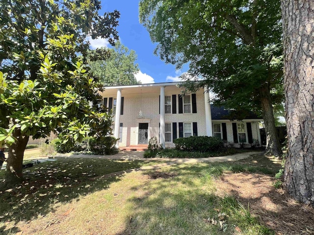 neoclassical home featuring a front lawn