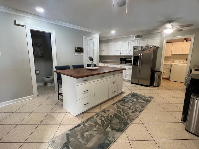 kitchen featuring wooden counters, stainless steel appliances, white cabinetry, and washer / clothes dryer