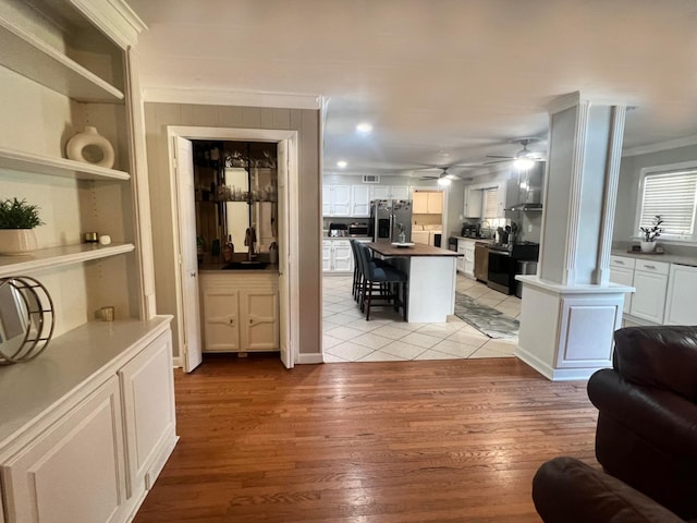 interior space with ceiling fan, sink, light hardwood / wood-style floors, and ornamental molding