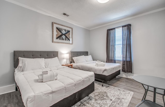 bedroom with a textured ceiling, hardwood / wood-style flooring, and ornamental molding