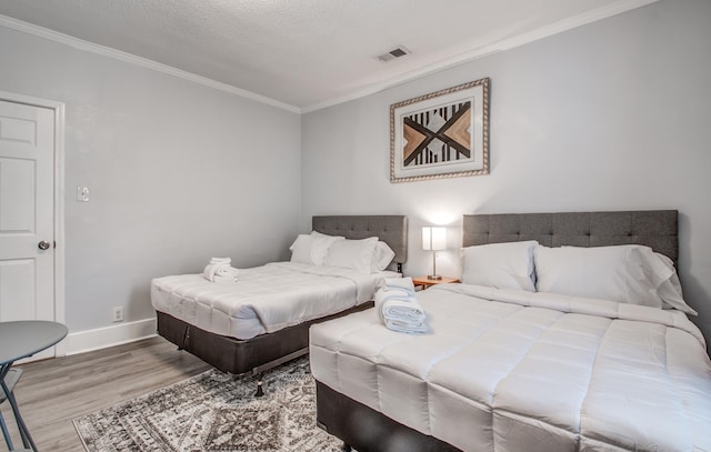 bedroom featuring ornamental molding, a textured ceiling, and light hardwood / wood-style flooring