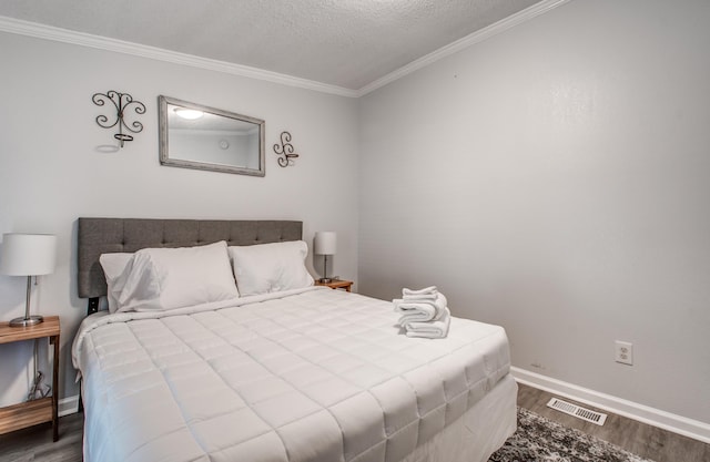 bedroom featuring ornamental molding, a textured ceiling, and hardwood / wood-style flooring