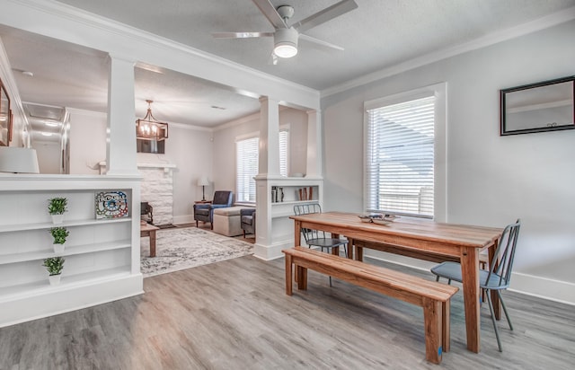 dining space featuring hardwood / wood-style flooring, ceiling fan with notable chandelier, crown molding, and a textured ceiling