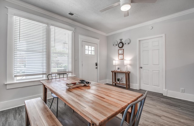 dining space featuring hardwood / wood-style floors, crown molding, and a textured ceiling