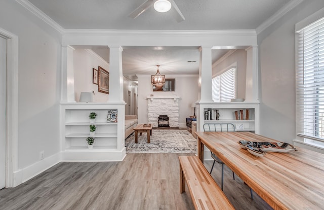 dining room with ceiling fan with notable chandelier, crown molding, a textured ceiling, a fireplace, and wood-type flooring