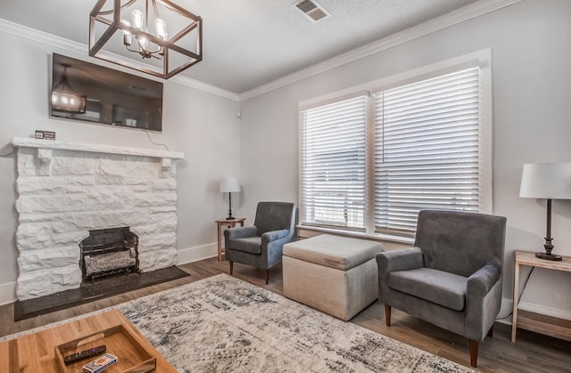 sitting room featuring a stone fireplace, crown molding, dark hardwood / wood-style flooring, and a notable chandelier