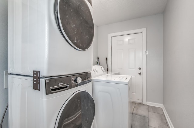 laundry room featuring stacked washing maching and dryer, a textured ceiling, and light tile patterned floors