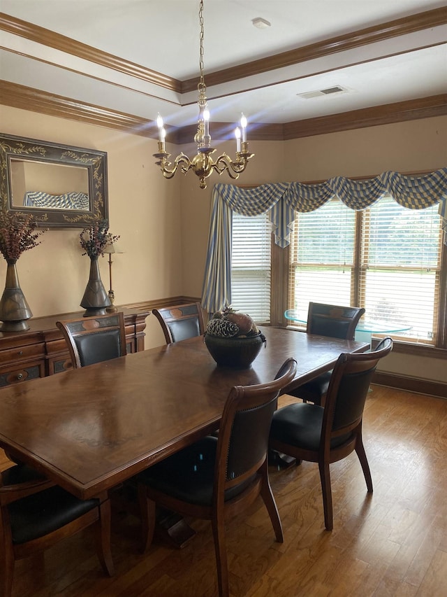 dining space featuring wood-type flooring, an inviting chandelier, and ornamental molding