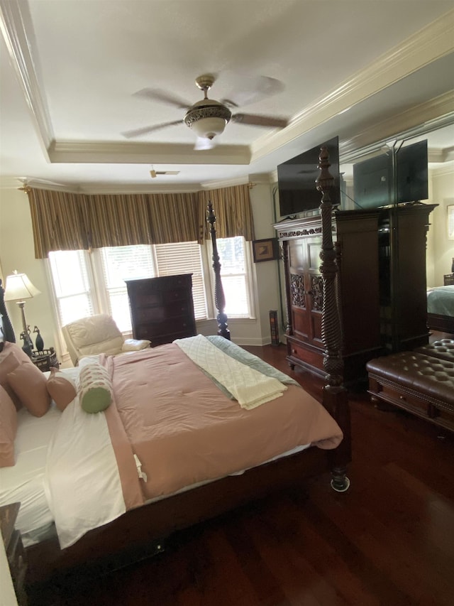 bedroom featuring ceiling fan, dark hardwood / wood-style floors, a tray ceiling, and multiple windows