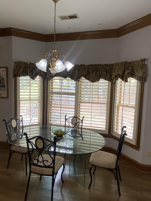 dining space featuring ornamental molding, hardwood / wood-style flooring, and a notable chandelier