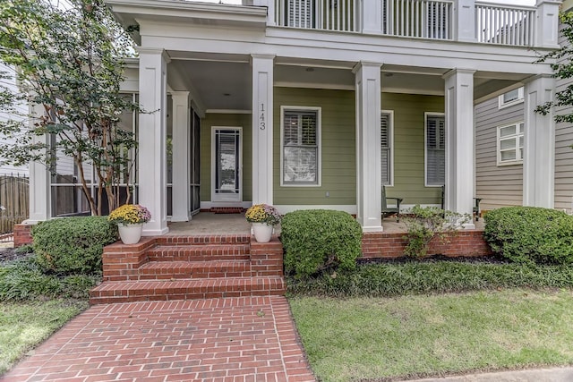 entrance to property featuring a porch and a balcony