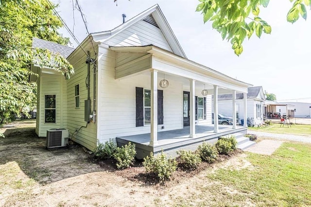 view of front of home featuring central AC unit, a porch, and a front yard