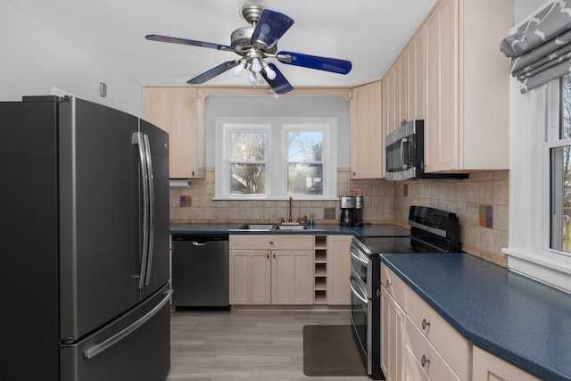 kitchen featuring decorative backsplash, stainless steel appliances, ceiling fan, sink, and light hardwood / wood-style floors