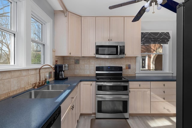 kitchen with backsplash, sink, ceiling fan, light wood-type flooring, and stainless steel appliances