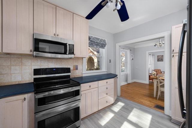 kitchen featuring decorative backsplash, stainless steel appliances, ceiling fan with notable chandelier, and light hardwood / wood-style floors