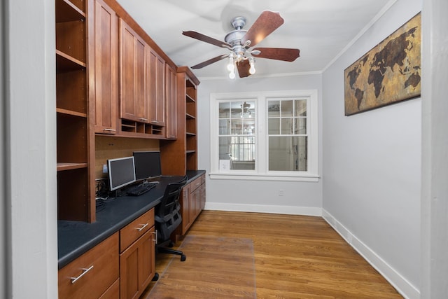 office area with built in desk, light hardwood / wood-style flooring, ceiling fan, and ornamental molding