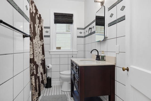 bathroom with vanity, tile walls, and toilet