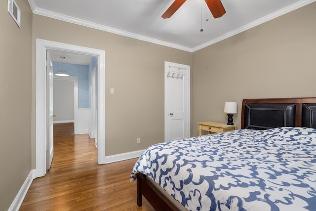 bedroom featuring ceiling fan, crown molding, and wood-type flooring