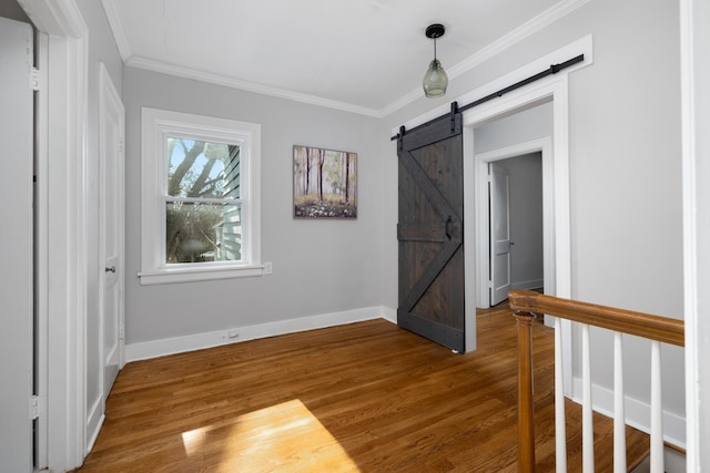 interior space with hardwood / wood-style floors, a barn door, and crown molding