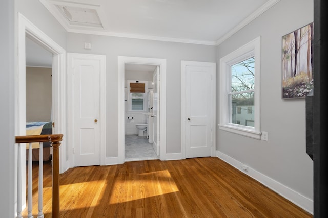 unfurnished bedroom with ensuite bath, crown molding, and wood-type flooring