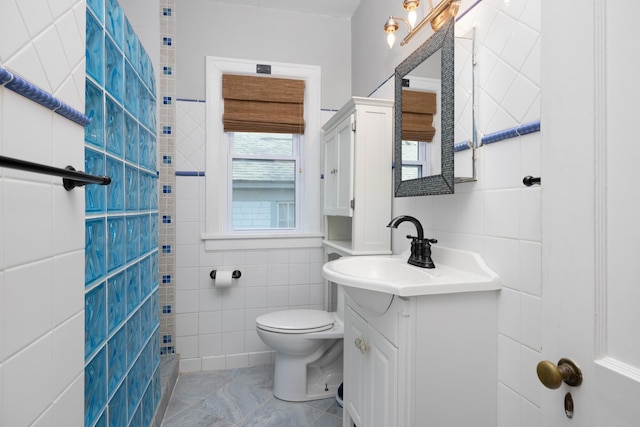 bathroom featuring tile patterned floors, vanity, toilet, and tile walls