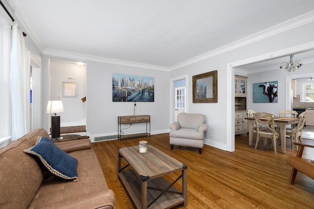 living room with wood-type flooring, crown molding, and a chandelier