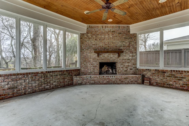 unfurnished sunroom with ceiling fan, a wealth of natural light, and wood ceiling