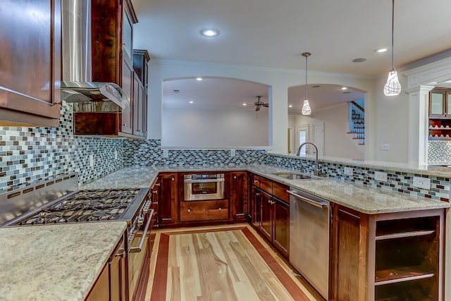 kitchen with light stone countertops, appliances with stainless steel finishes, sink, pendant lighting, and light hardwood / wood-style floors