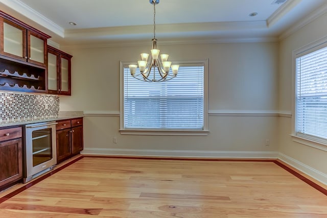 kitchen featuring backsplash, decorative light fixtures, light hardwood / wood-style flooring, a notable chandelier, and beverage cooler