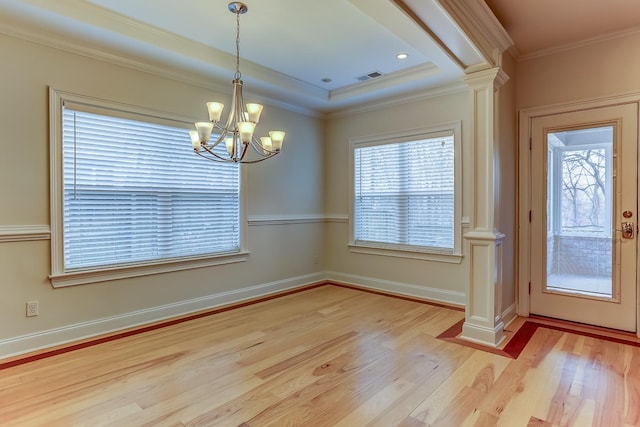 unfurnished dining area with decorative columns, crown molding, light hardwood / wood-style flooring, and a notable chandelier