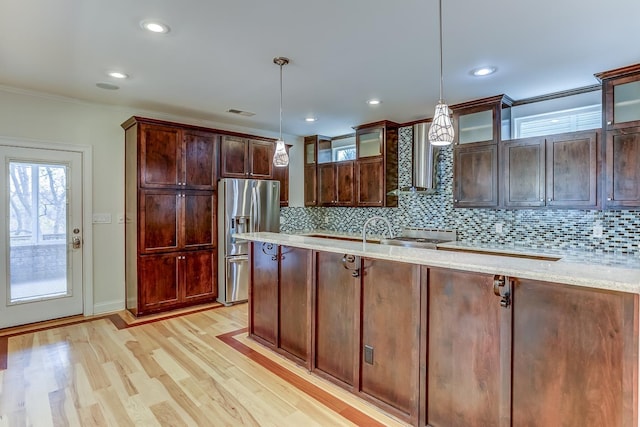 kitchen featuring stainless steel fridge, wall chimney exhaust hood, pendant lighting, and light wood-type flooring