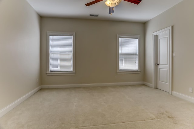 spare room with ceiling fan, plenty of natural light, and light colored carpet