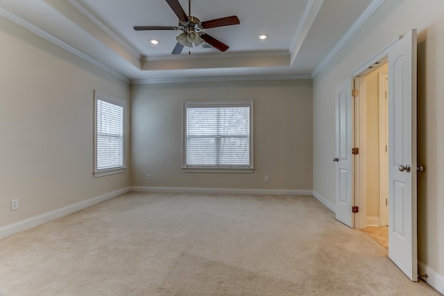 carpeted empty room featuring ceiling fan, a raised ceiling, and ornamental molding