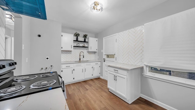 kitchen featuring white electric range oven, light wood-type flooring, white cabinetry, and sink