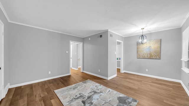 spare room featuring crown molding, hardwood / wood-style floors, and a notable chandelier