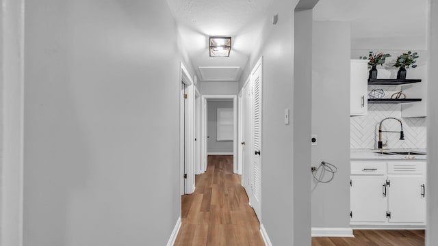 corridor with light wood-type flooring and sink